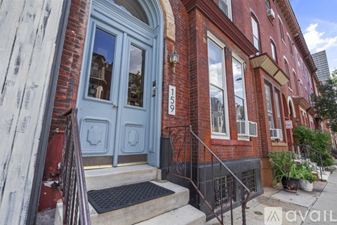 A red brick building with a blue door and a black metal railing.