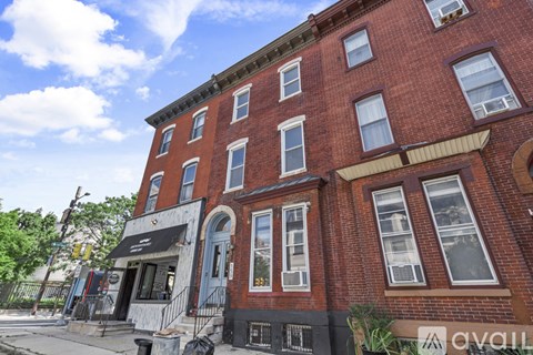 A red brick building with a black awning and a white sign with the letters "avail" on it.