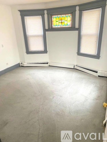 A room with a grey floor and a stained glass window.