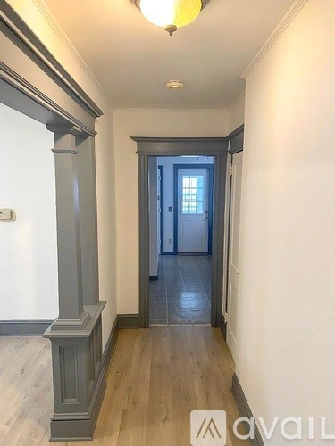 A hallway with a wooden floor and a closed door at the end.