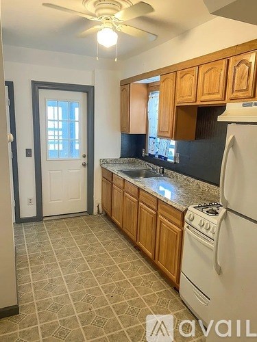 A kitchen with a white refrigerator and wooden cabinets.