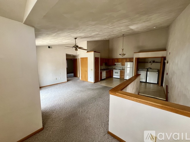 A spacious room with a ceiling fan and a kitchen area in the background.