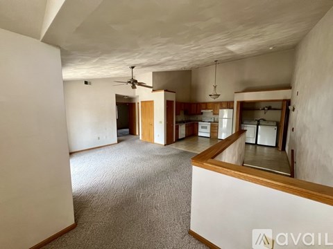 A spacious room with a ceiling fan and a kitchen area in the background.