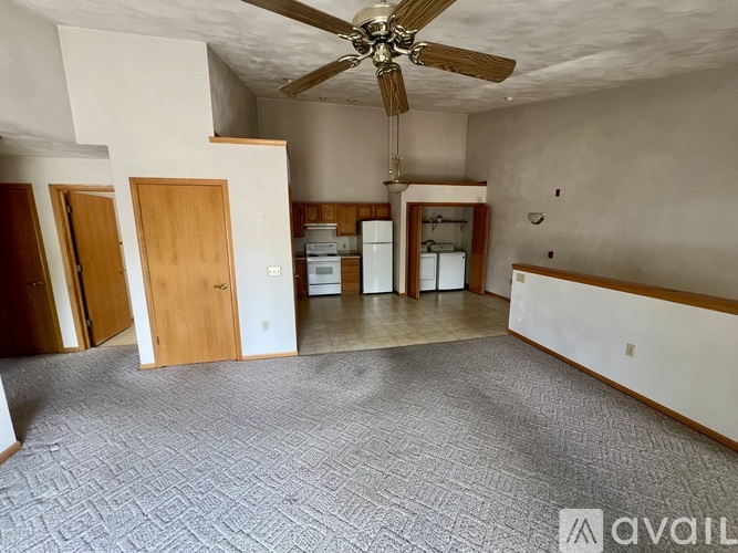 A spacious room with a ceiling fan and a carpeted floor.