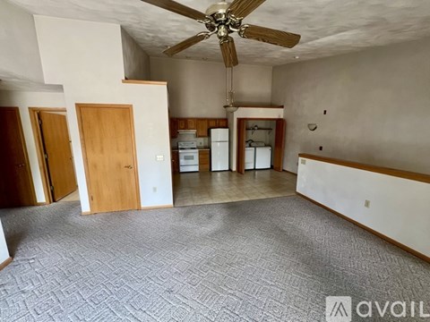 A spacious room with a ceiling fan and a carpeted floor.