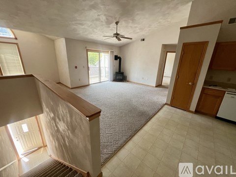 A spacious living room with a ceiling fan and a staircase leading to the upper floor.