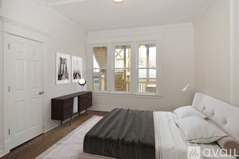 A bedroom with a large bed and a window with blinds.