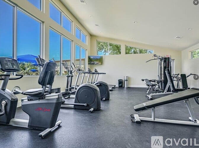 A gym with treadmills, elliptical machines, and a weight bench.