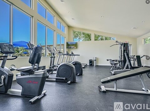 A gym with treadmills, elliptical machines, and a weight bench.
