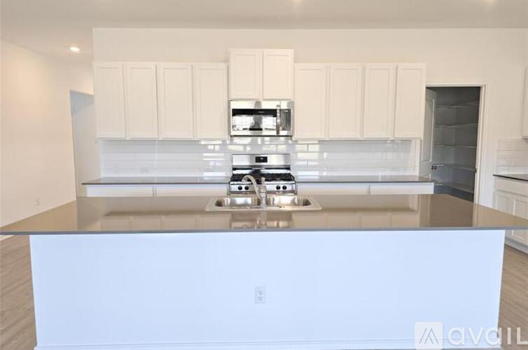 A modern kitchen with white cabinets and a stainless steel island.