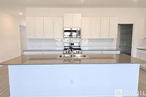 A modern kitchen with white cabinets and a stainless steel island.