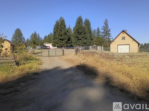 A dirt road leads to a house with a garage.