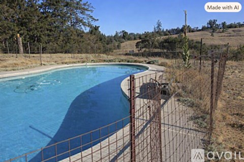 A pool surrounded by a fence with trees in the background.