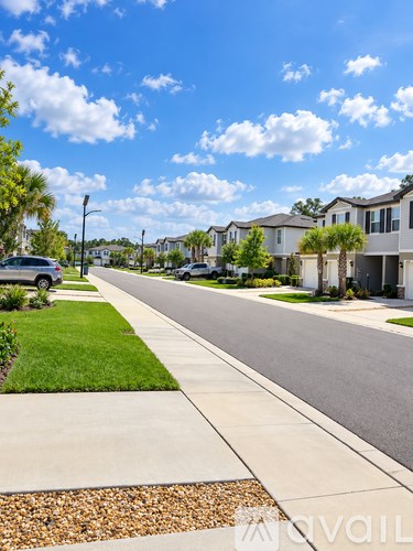 A street view of a residential area with houses on both sides and a car parked on the sidewalk.