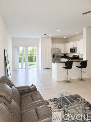 A modern kitchen with a bar stool and a fridge.