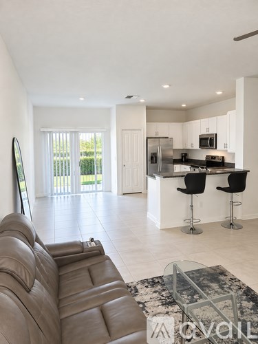 A modern kitchen with a bar stool and a fridge.