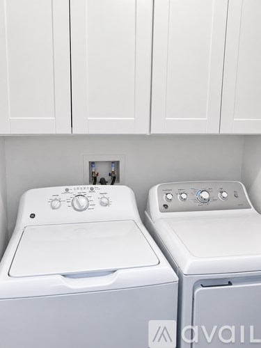 Two white front loading washing machines in a laundry room.