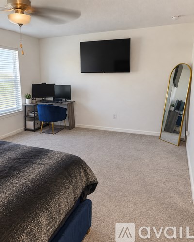 A bedroom with a bed, desk, and television.