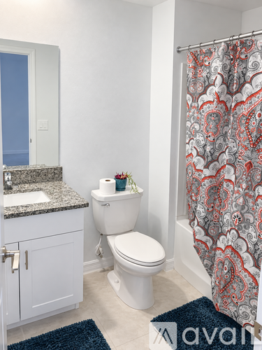 A bathroom with a toilet, sink, and shower curtain.