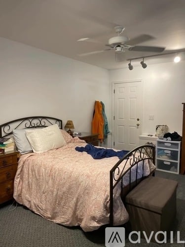 A bedroom with a bed, dresser, and a ceiling fan.