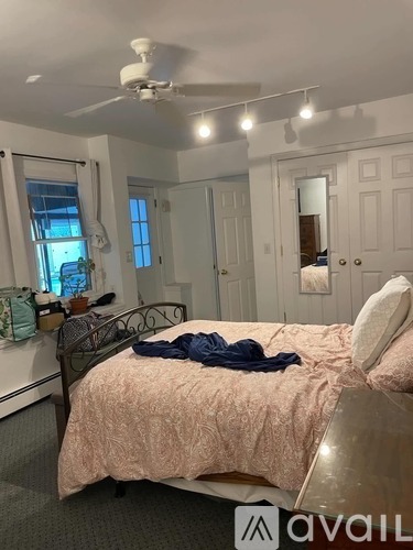 A bedroom with a bed, a ceiling fan, and a window.