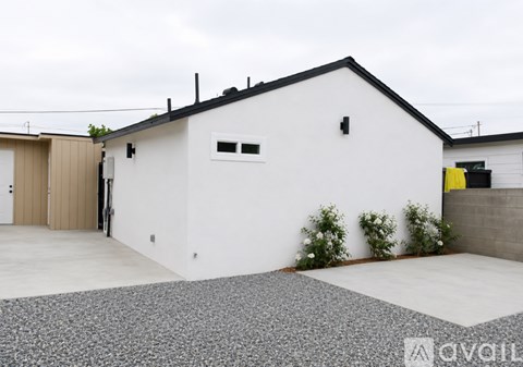 A modern house with a white exterior and a gravel driveway.