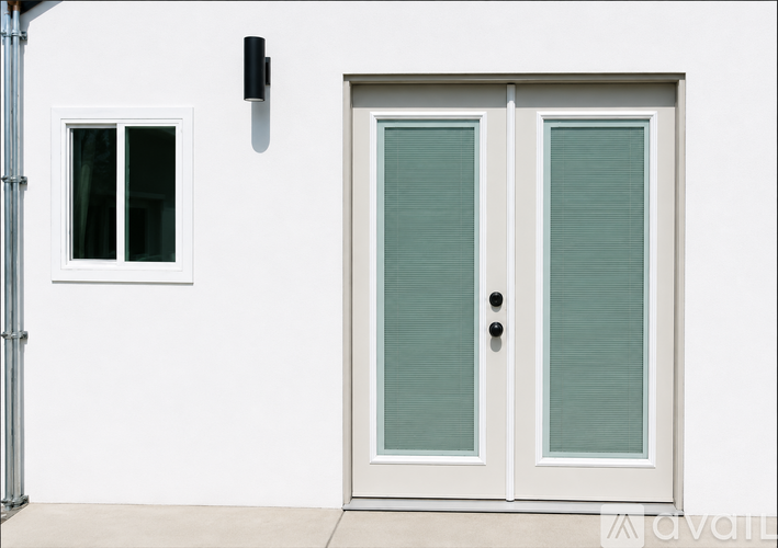 A white door with a window to the left and a black handle.