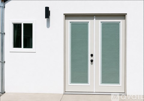 A white door with a window to the left and a black handle.