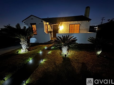 A house with a lit pathway in front of it at night.