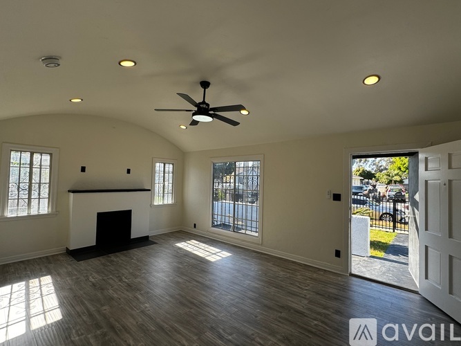 A spacious living room with a fireplace and a ceiling fan.