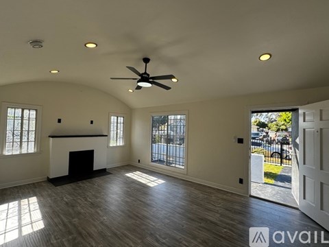 A spacious living room with a fireplace and a ceiling fan.