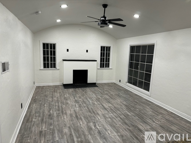 A spacious room with a fireplace and a ceiling fan.