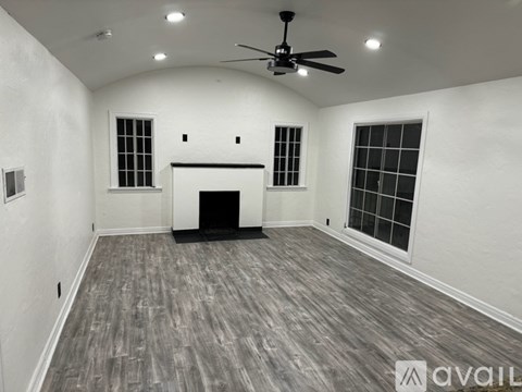 A spacious room with a fireplace and a ceiling fan.