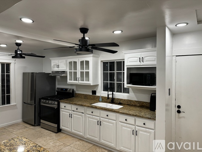 A kitchen with white cabinets and a black refrigerator.