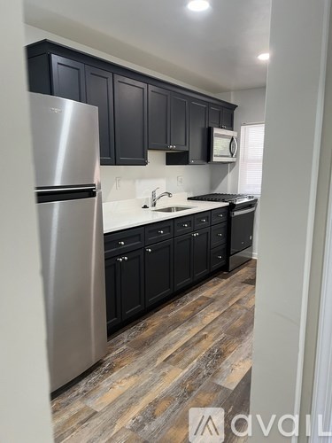 A kitchen with a stainless steel refrigerator and black cabinets.