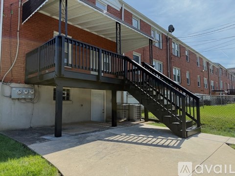 A balcony with a staircase leading to a building with a brick facade.