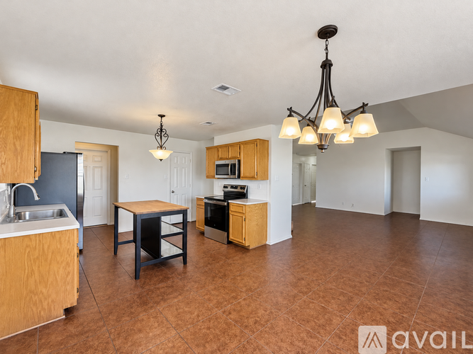 A kitchen with brown floors and a wooden table.