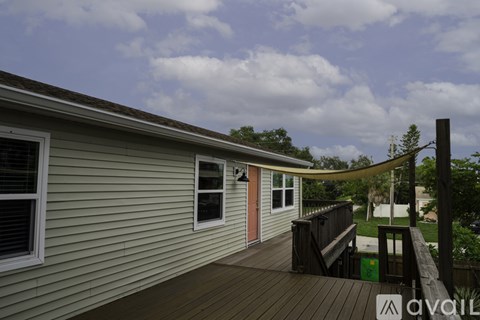 A house with a deck and a small tree.