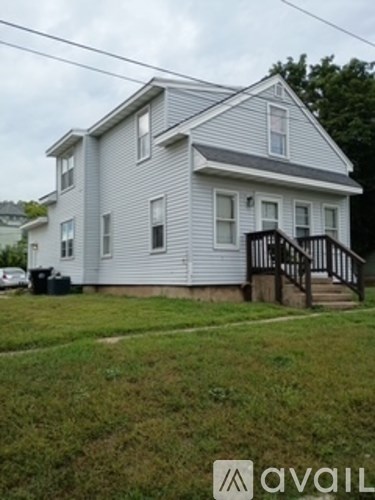 A house with a grey roof and a white wall with a black railing.