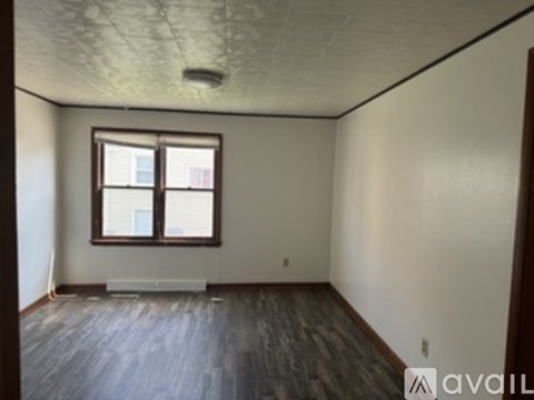 A room with a window and wooden floors is available for rent.