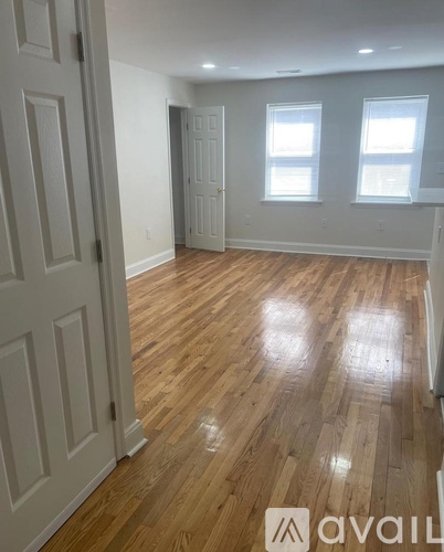 A room with wooden flooring and two windows.