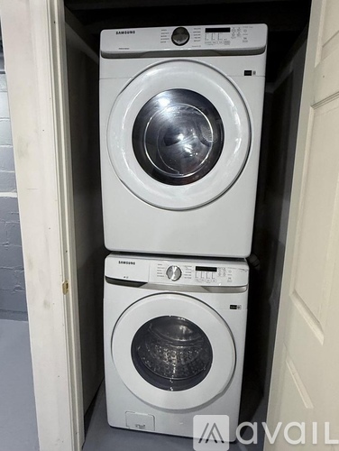 Two Samsung front load washing machines stacked on top of each other in a small space.