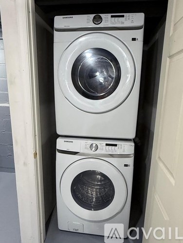 Two Samsung front load washing machines stacked on top of each other in a small space.