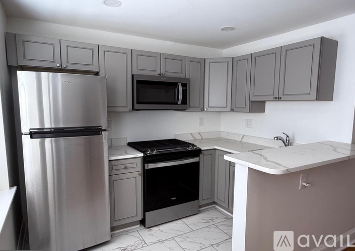 A kitchen with a refrigerator, microwave, oven, and sink.