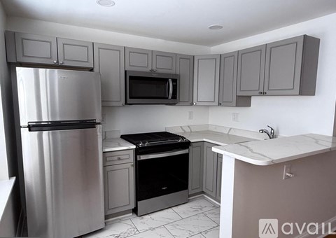A kitchen with a refrigerator, microwave, oven, and sink.