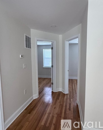 A hallway with wood floors and white walls.