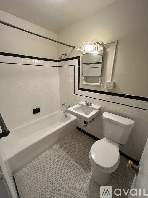 A white toilet is in a bathroom with a white tub and sink.