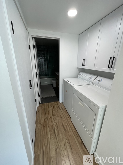 A small kitchen with white appliances and wooden floors.