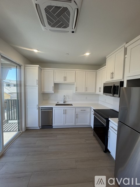 A kitchen with white cabinets and a black counter top.