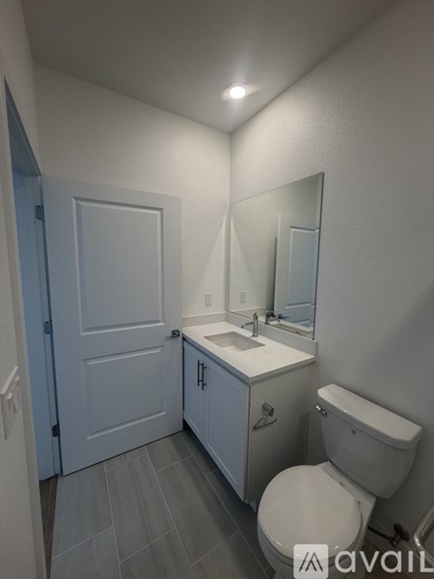A bathroom with a toilet, sink, and mirror.